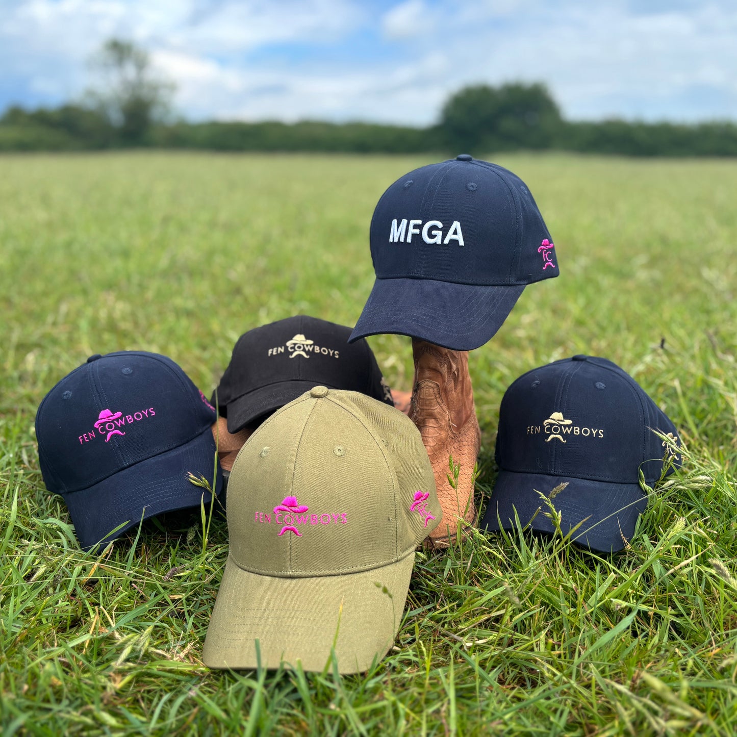Five baseball caps with various logos on a grassy field