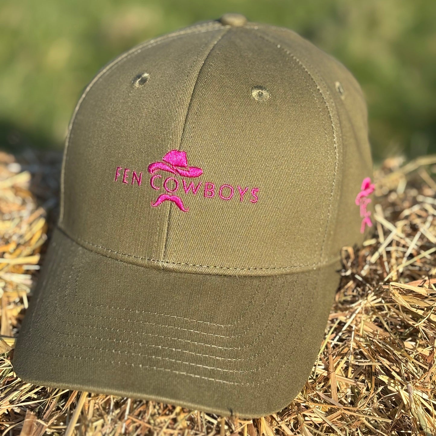 Green cap with pink logo on a hay bale
