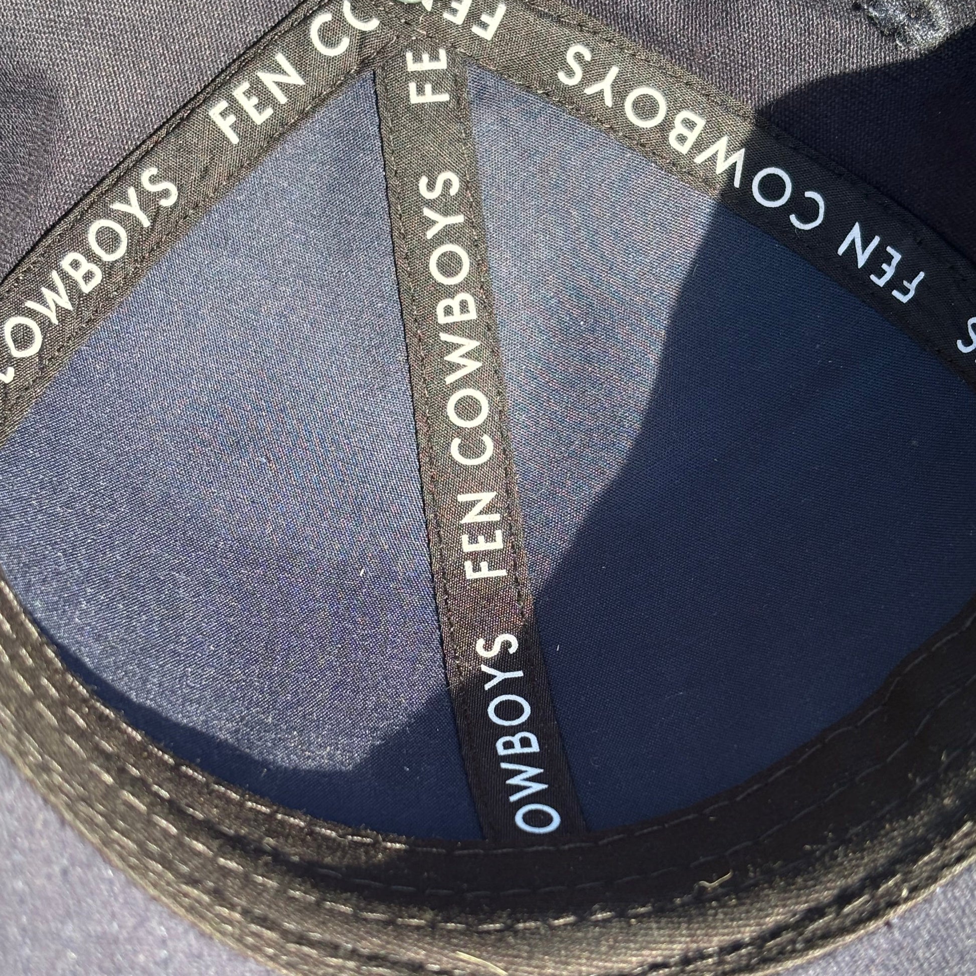 Close-up of a cap with 'Cowboys Fan' branding on a gray background