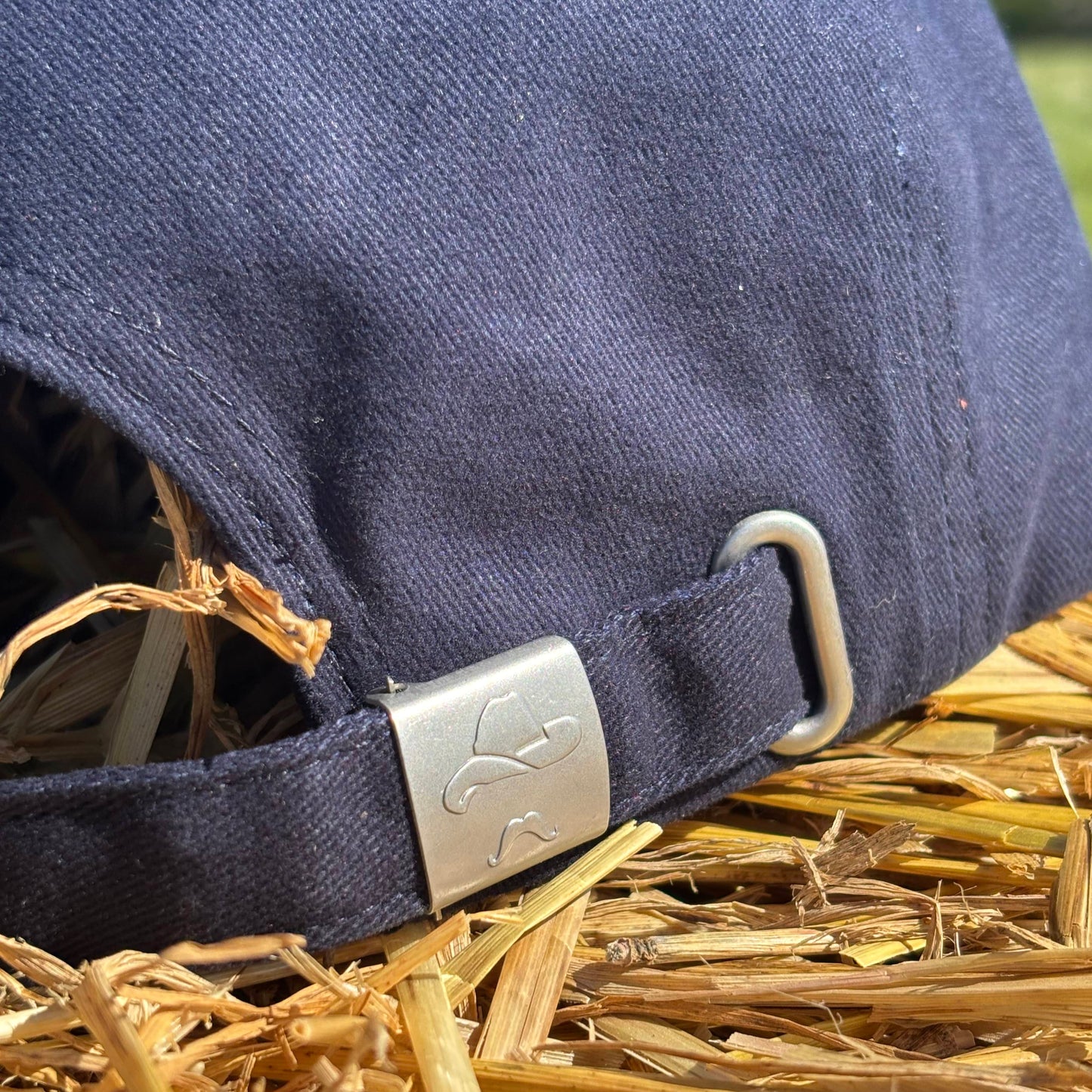 Navy blue strap with a metal buckle on hay