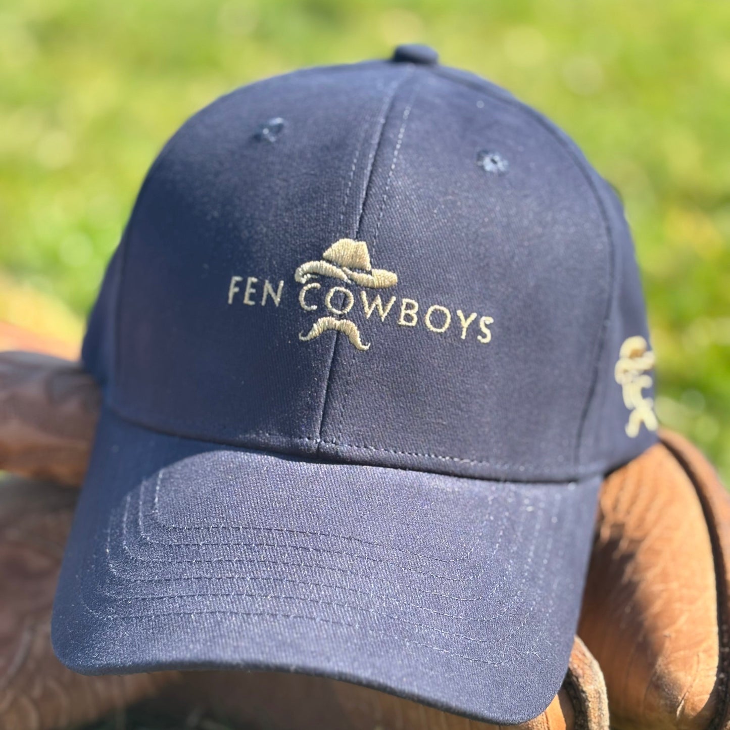 Navy blue cap with 'Fen Cowboys' logo on a grass background