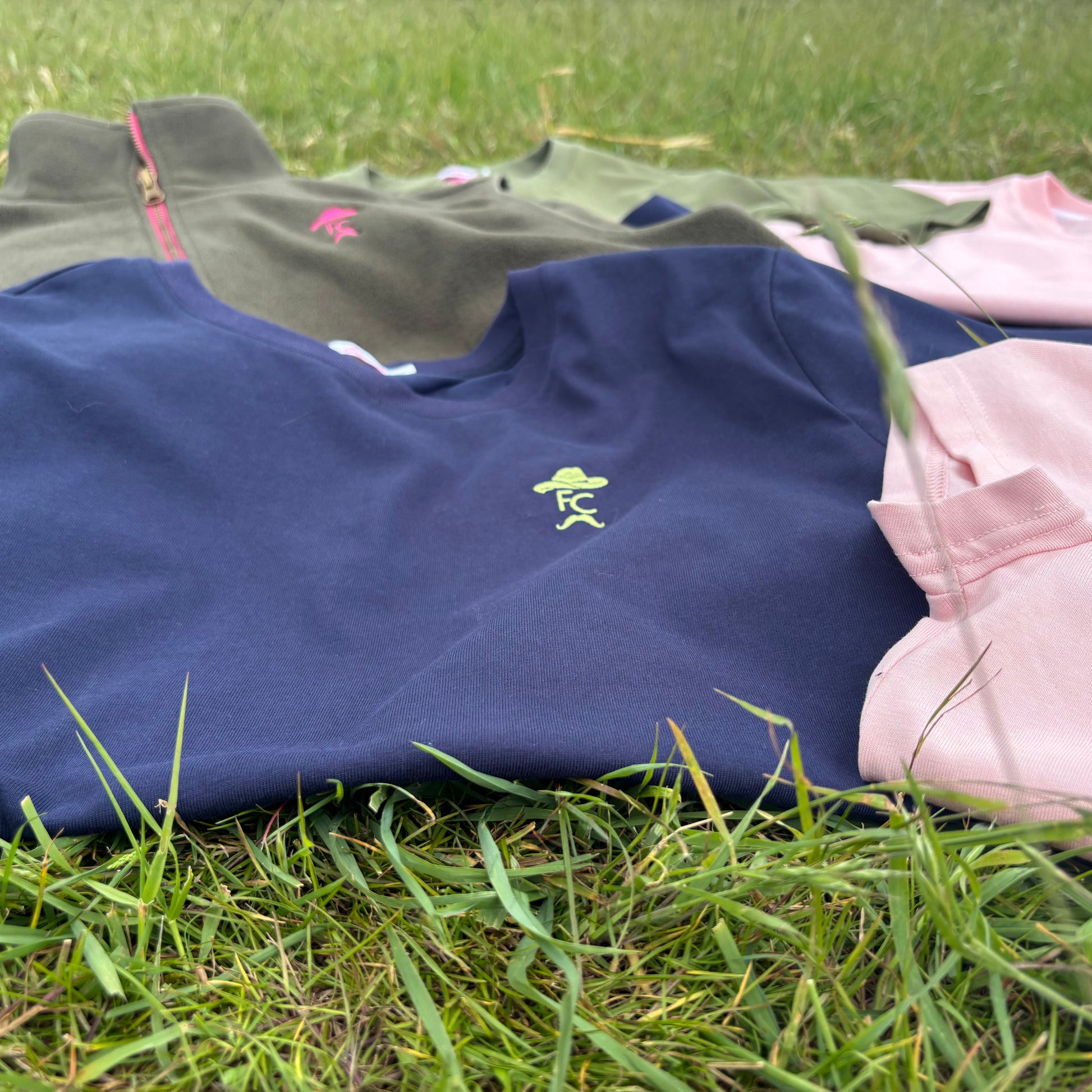 Clothing items including a navy blue shirt with a logo on grass