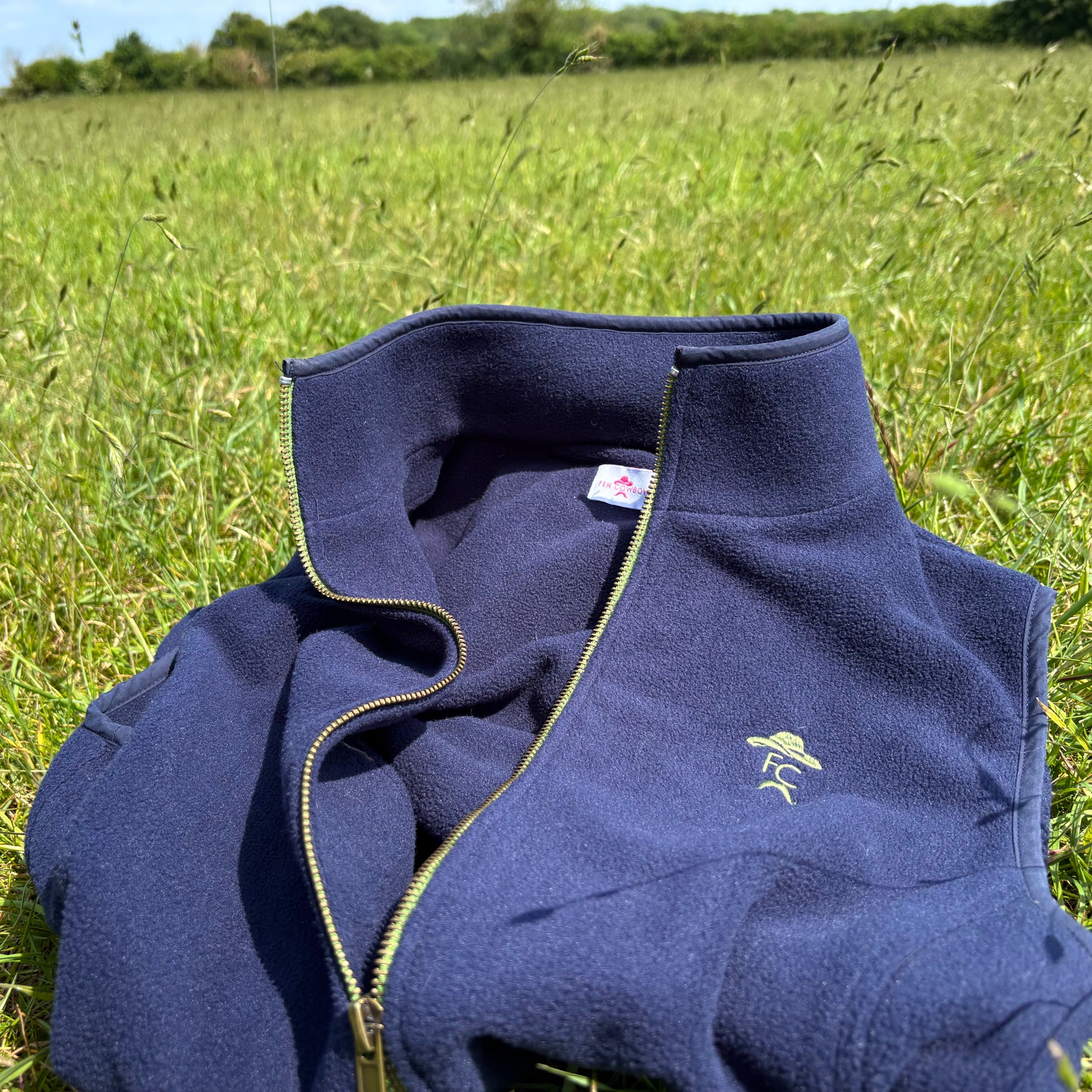 Navy blue fleece vest on grass with visible brand logo