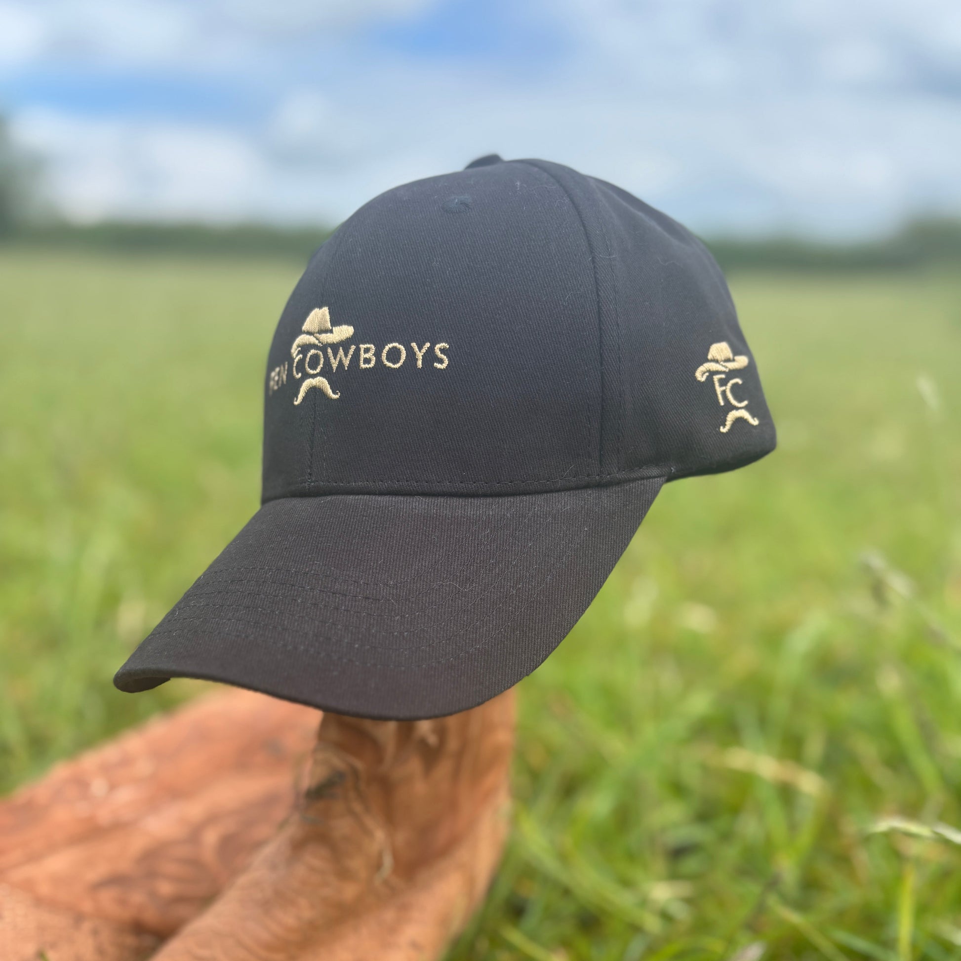 Black cap with 'Cowboys' logo on a grassy field