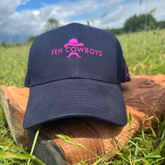 Navy blue cap with pink logo on a brown boot in grass