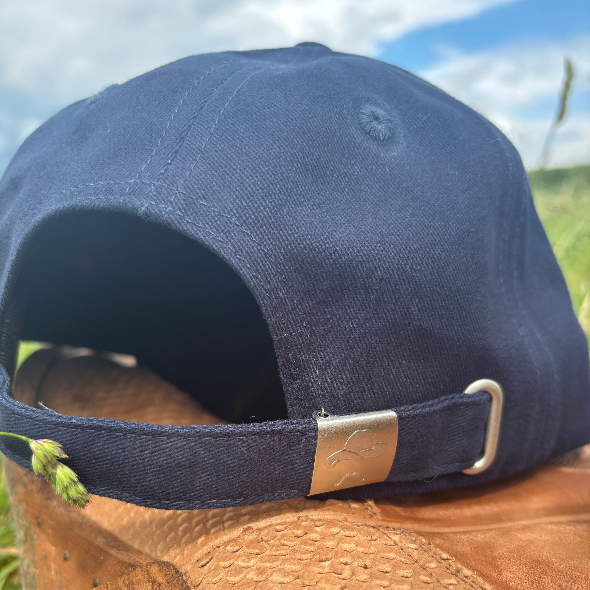 Navy blue cap with a gold buckle on a blurred natural background