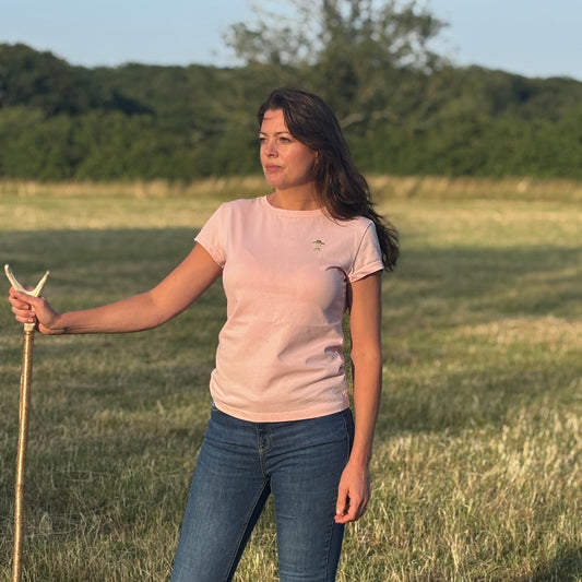 Woman standing in a field holding a bow and arrow