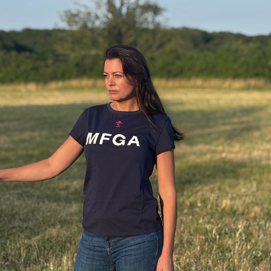 Woman wearing a navy blue t-shirt with 'MFGA' logo standing in a field.