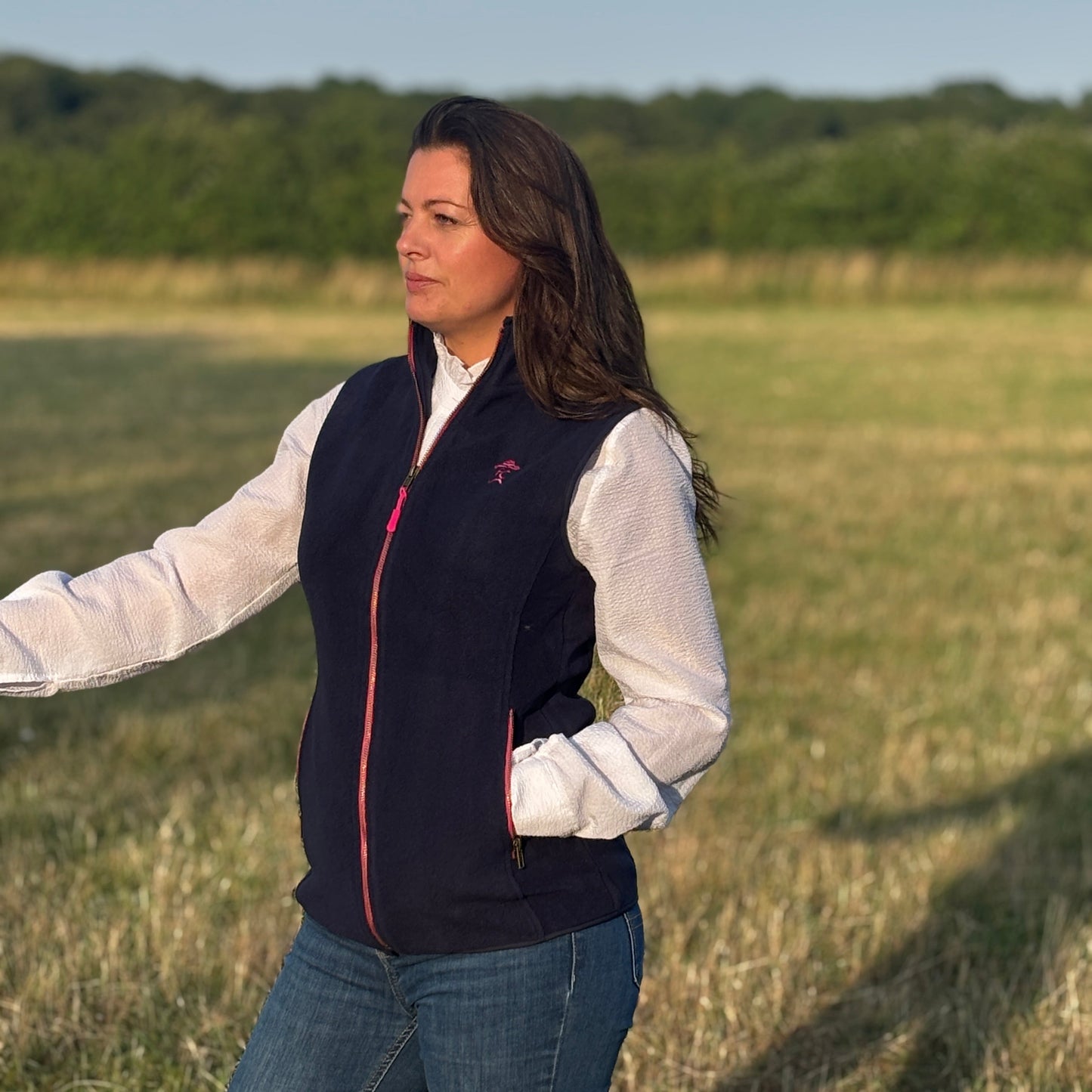 Woman wearing a navy vest with a logo in an open field