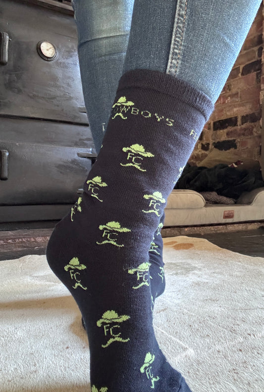 Dark blue sock with green patterns and text, worn indoors.